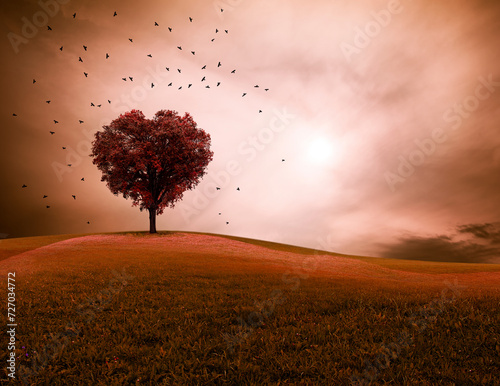 Baum in Herzform in einer Landschaft mit dramatischem Himmel und auffliegende...