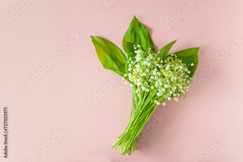 May Day symbol: bouquet of lilies-of-the-valley on a pink background; flat lay, copy space photo
