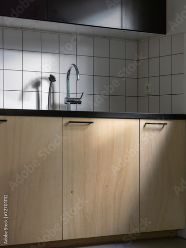 Interior of a modern kitchen in the Netherlands. Wooden cupboards with white tiles and black cupboards.