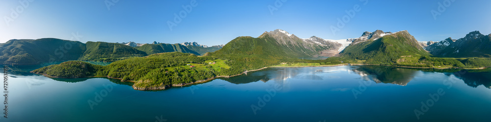 Expansive hyper panorama of Svartisen Glacier, where the pristine waters of the fjord flawlessly reflect the Saltfjell mountain range under the clear Norwegian sky