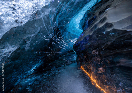 Blue glacial ice cave illuminated by orange light in Iceland photo