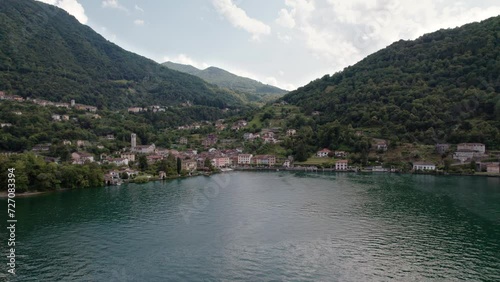 Drone flies over the lake and you can see the small fishing village of Osteno in Italy. Breathtaking scenery on a beautiful sunny summer day. photo