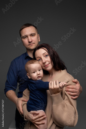 close-up portrait of happy parents hugging their little son and holding them in their arms. minimalistic photography on a dark background. father and mother with little son