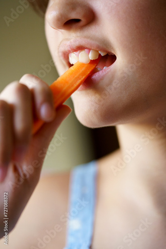 Crop anonymous girl biting organic healthy carrot slice