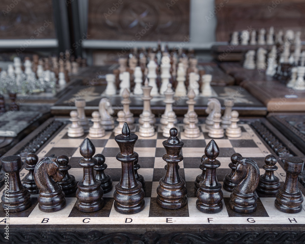 Collection of many chess boards of various sizes with row of black chess in foreground Collection of many chess boards of various sizes with row of black chess in foreground