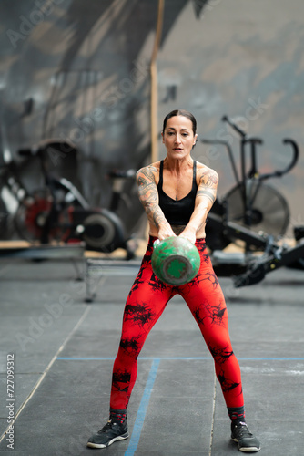 Woman performing kettlebell swing exercise in a gym