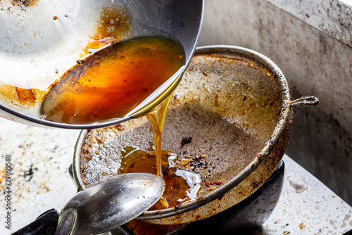 Foto Pouring used cooking oil from frying pan into colander