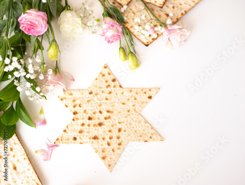 Passover. Traditional Matzo shape of star Magen David  decorate by pink flowers on white background. top view. Holiday of Jewish people, Spring Holiday. Fasting time