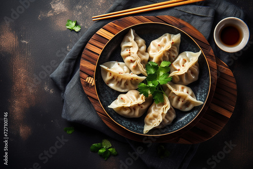 Steamed dumplings on a round plate with dipping sauce and chopsticks
