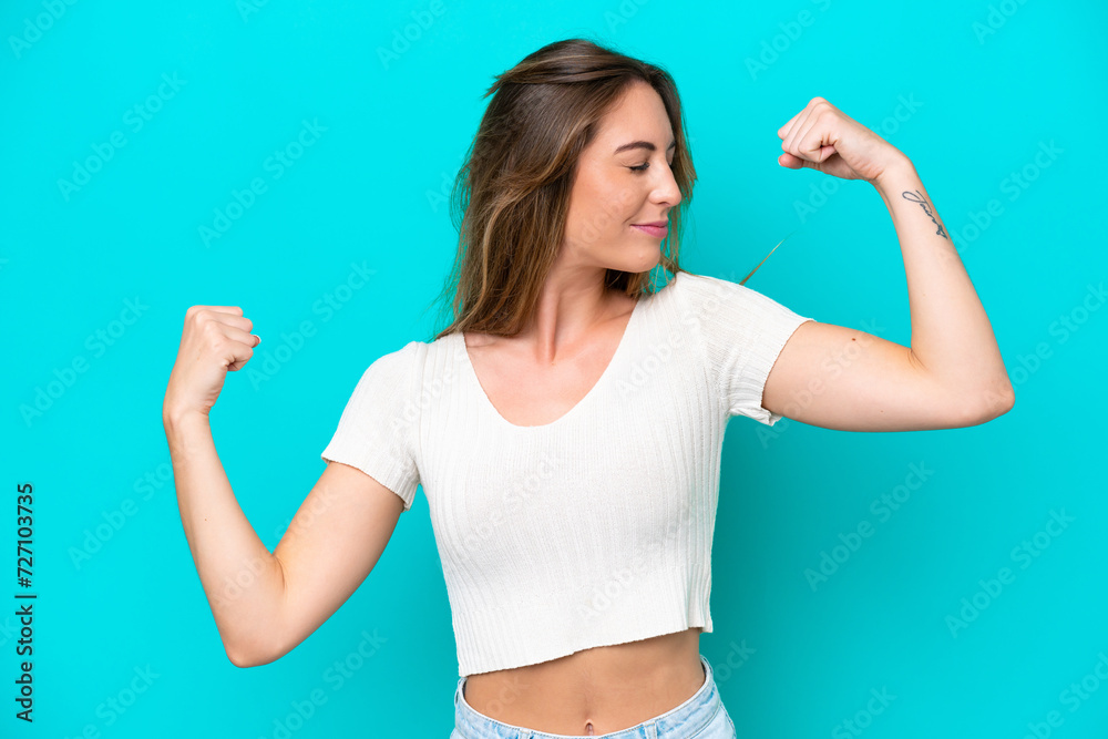 Fototapeta premium Young caucasian woman isolated on blue background doing strong gesture