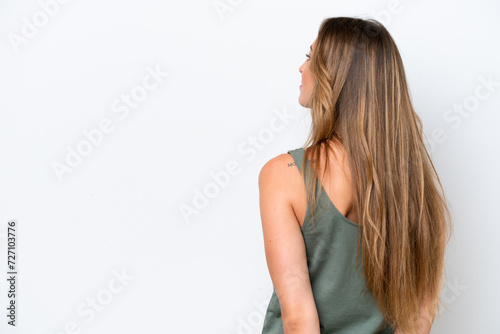 Young caucasian woman isolated on white background in back position and looking back