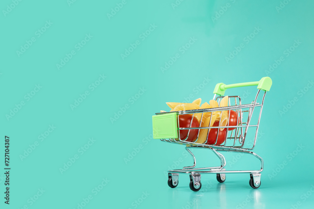 Grocery cart with food on green background, supermarket shopping, fresh produce, healthy nutrition