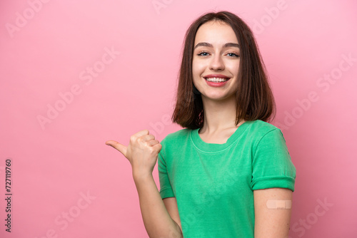 Young Ukrainian woman wearing a band aids pointing to the side to present a product © luismolinero