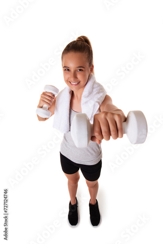 Healthy teen girl with dumbbells working out with towel on shoulder. Isolated on white background. fitness gym concept. Wide angle shot