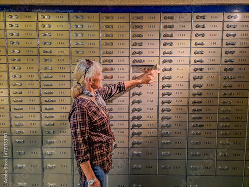 A older woman opens her secret box with deposits in a bank vault. Pensioner.