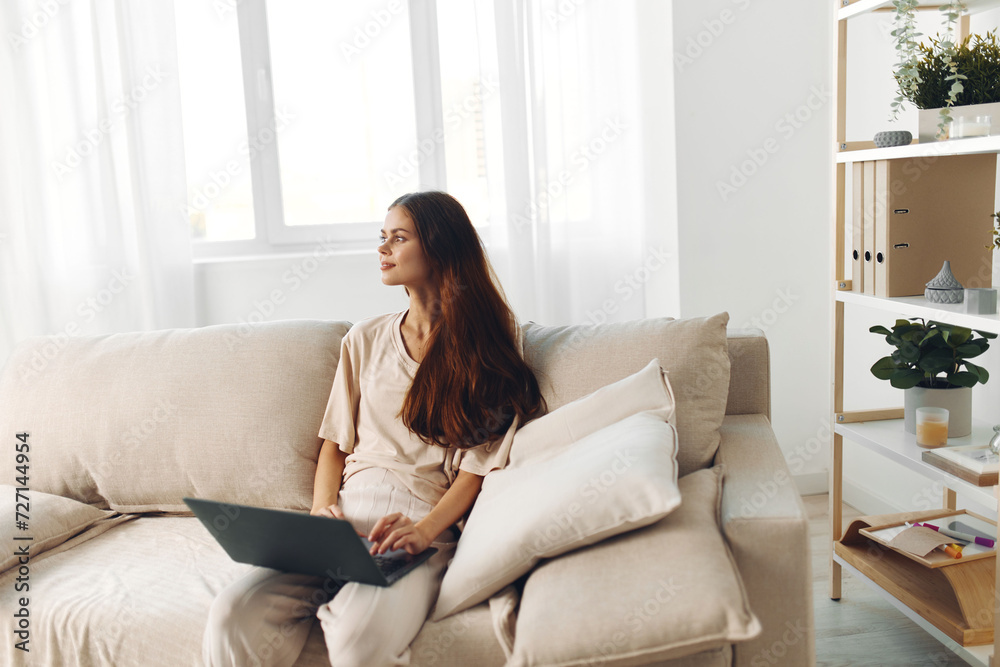 Smiling woman working on laptop in cozy home office, surrounded by modern technology and comfortable lifestyle Smiling woman working on laptop in cozy home office, surrounded by modern technology and comfortable lifestyle