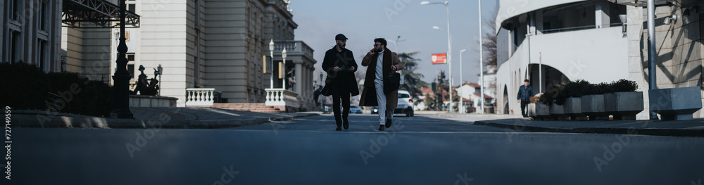Two stylish men in modern attire engage in conversation while walking down a bustling city street, showcasing everyday urban life and casual fashion. Two stylish men in modern attire engage in conversation while walking down a bustling city street, showcasing everyday urban life and casual fashion.