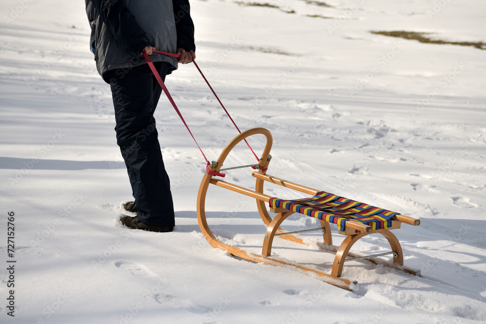 A man pulls a sledge up a hill in the winter tobogganing