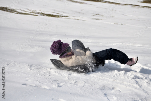 Obraz na płótnie A child slides down a hill in the snow in winter w salonie