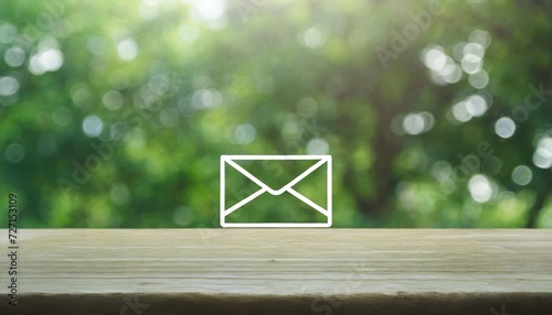 mail icon on wooden table over blur green tree in garden contact us concept