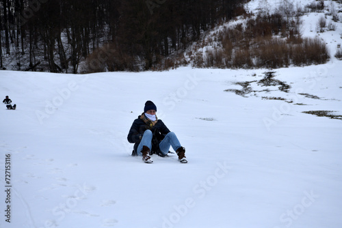 Obraz na płótnie An adult woman sleds down a hill in the winter and brakes with her feet w salonie