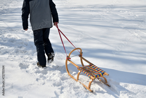 Obraz na płótnie A man pulls a sledge up a hill in the winter tobogganing w salonie