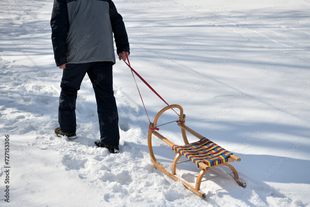 A man pulls a sledge up a hill in the winter tobogganing