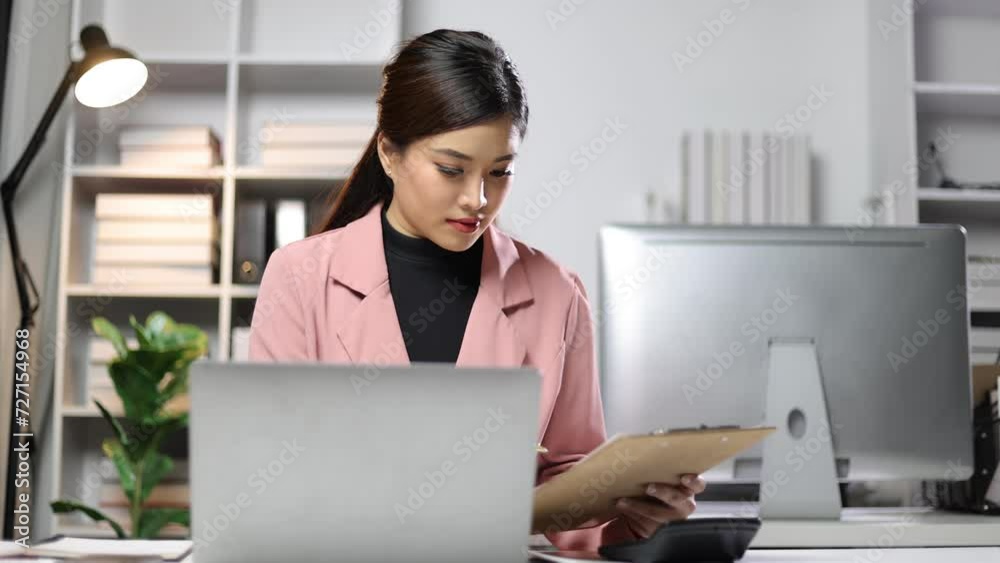 Attractive Asian businesswoman working on documents on laptop in office. Attractive Asian businesswoman working on documents on laptop in office.