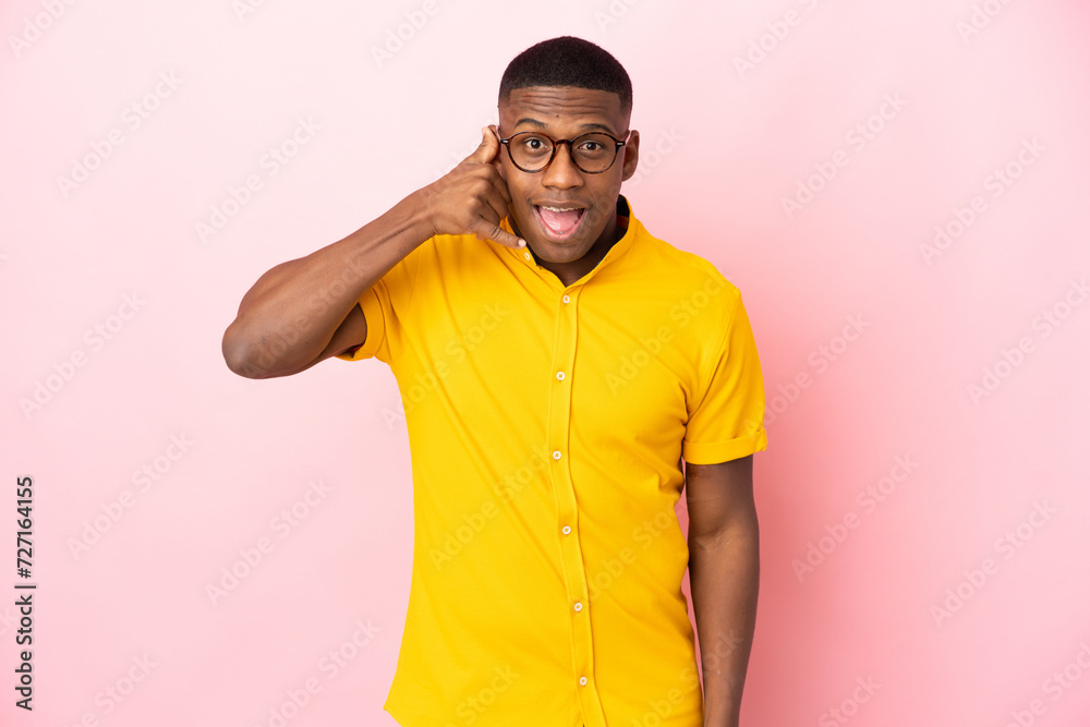 Young latin man isolated on pink background making phone gesture. Call me back sign Young latin man isolated on pink background making phone gesture. Call me back sign