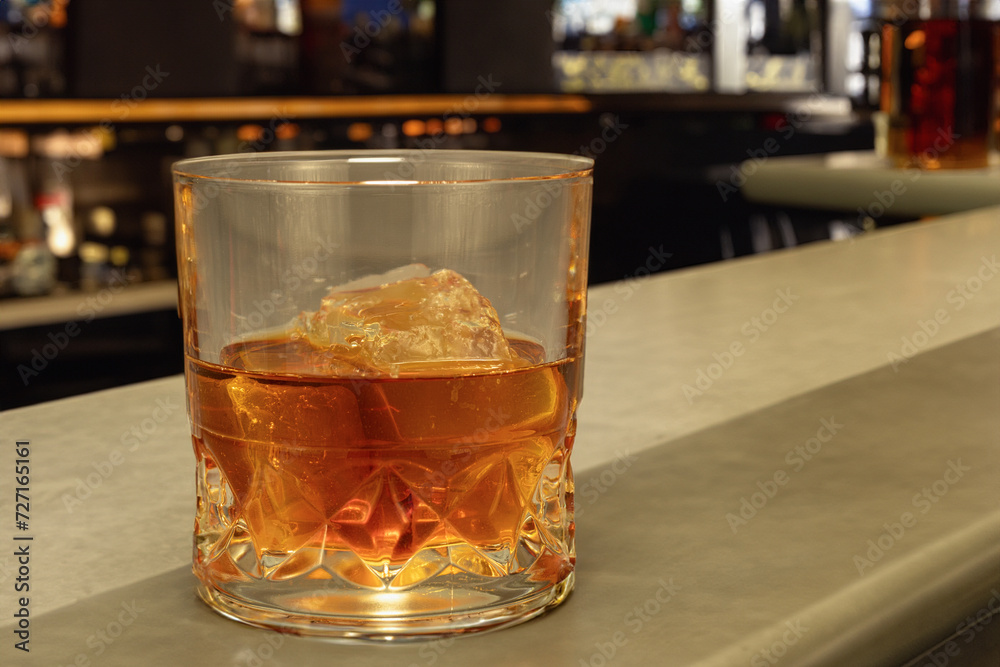 A glass of whiskey with ice. Background with copy space. A glass of alcohol on the bar counter. Generated by artificial intelligence