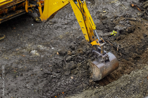Excavator bucket starts to dig the ground, beginning of construction, earthworks at the construction site, excavator work photo