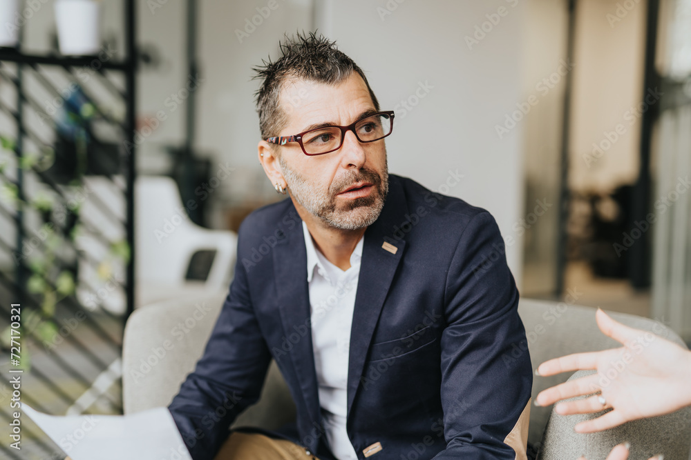 Fototapeta premium Businessman listening carefully to his partner explaining something. Business people collaborating in an office, analyzing statistics and planning for growth.