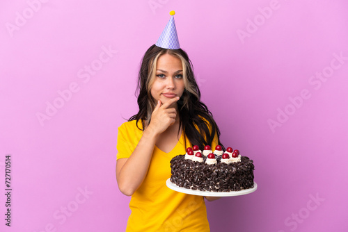 Teenager Russian girl holding birthday cake isolated on purple background thinking