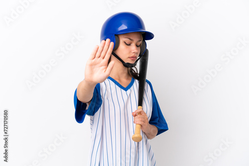 Baseball Russian girl player with helmet and bat isolated on white background making stop gesture and disappointed