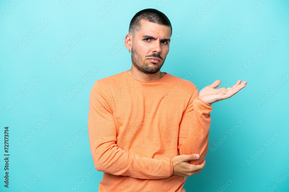 Young caucasian man isolated on blue background having doubts Young caucasian man isolated on blue background having doubts
