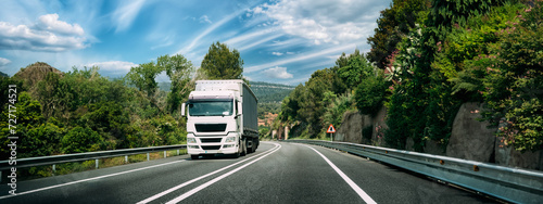 White Truck Or Tractor Unit, Prime Mover, Traction Unit In Motion On Road, Freeway. Asphalt Motorway Highway Against Background Of Hill Landscape. Business Transportation And Trucking Industry