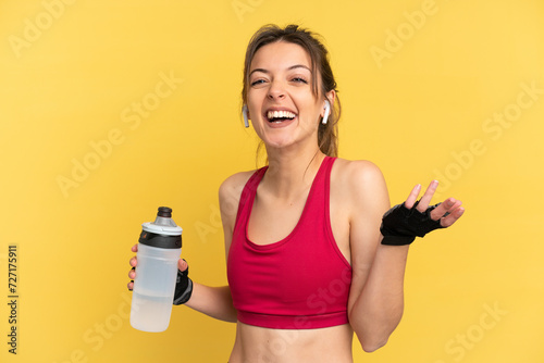 Young caucasian woman isolated on blue background with sports water bottle