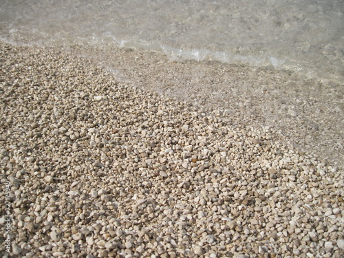 Macro view of gravel beach on the sun. Pebbles on the seaside. Close up of a stone on a sunny summer day. 