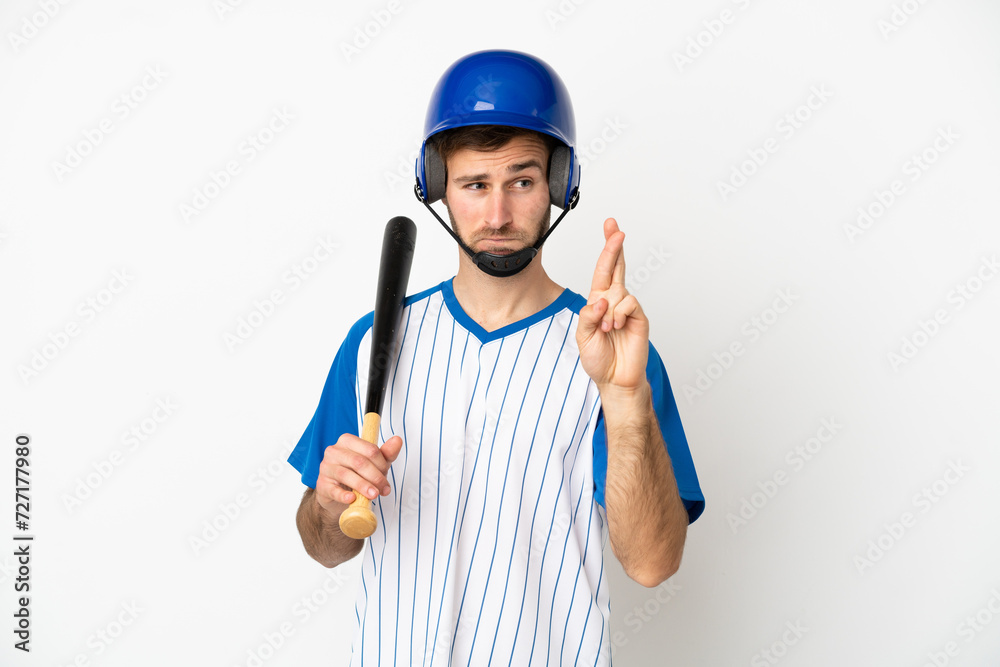 Young caucasian man playing baseball isolated on white background with fingers crossing and wishing the best