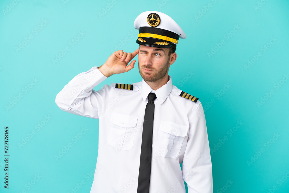 Airplane caucasian pilot isolated on blue background having doubts and with confuse face expression
