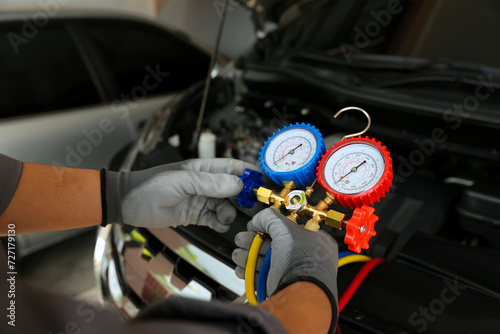 Car mechanic uses air refrigerant meter manifold gauge to check car air conditioner system heat problem and fix repairing and filling air refrigerant.