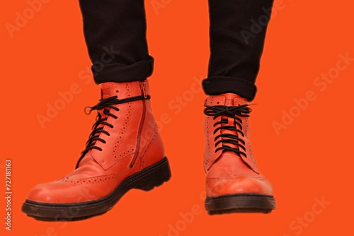 a man stands in orange shoes with black laces