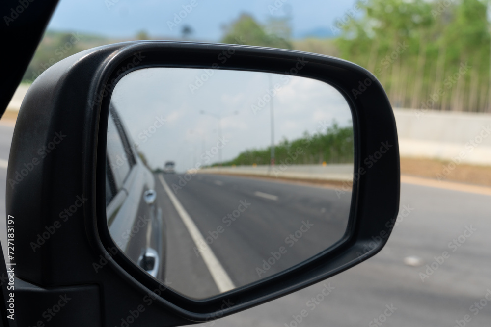 Mirror view of car travel on the asphalt road. Background on front with speed of asphalt road and instead of a roadside barrier and rubber trees.