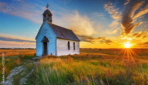 old abandoned white wooden chapel on prairie at sunset with clou