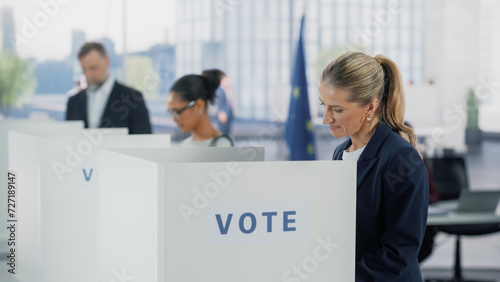 Portrait of a Beautiful Adult Woman Filling Out a Ballot in a Voting Booth on the Day of National Elections in the European Union. Diverse Men and Women Voting for Elected Officials in an EU Country photo