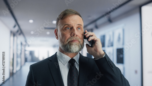 Portrait of a Handsome Middle Aged Businessman Talking on a Phone Call with Corporate Business Clients. Confident Company CEO Planning Successful Work Projects While Walking to the Office