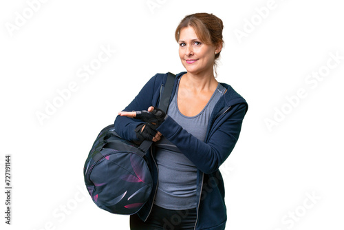 Middle-aged sport woman with sport bag over isolated background presenting an idea while looking smiling towards