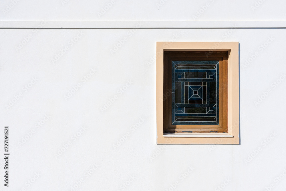 Window with color mosaic on white textured wall.