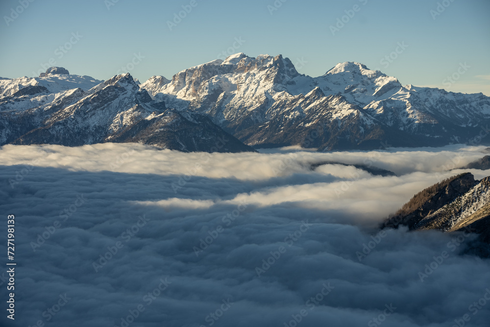 Mountain above clouds, Civetta resort. Panoramic view of the Dolomites mountains in winter, Italy. Ski resort in Dolomites, Italy. Aerial  drone view of ski slopes and mountains in alps.