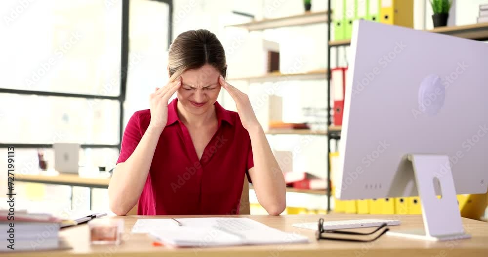 Attractive woman at office desk massaging temples for headaches ...